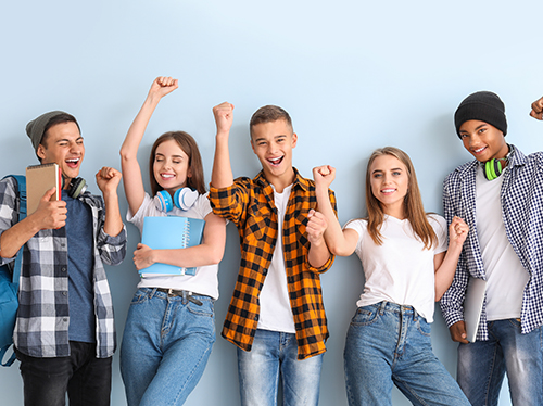 Fünf junge Menschen im Teenageralter freuen sich und haben teilweise Schulunterlagen in den Händen.