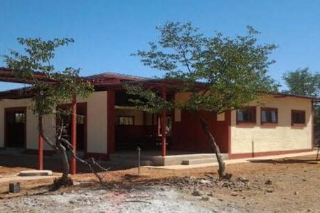 Das Bild zeigt ein einstöckiges Schulgebäude mit Bäumen davor in Namibia.