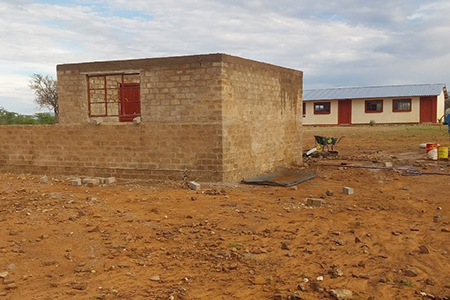 Das Bild zeigt ein einstöckiges Schulgebäude mit Bäumen davor in Namibia.